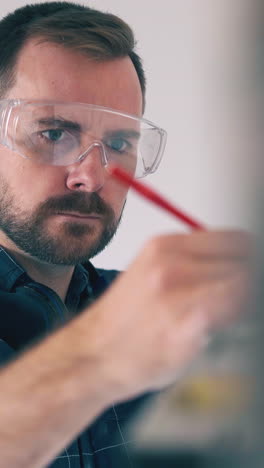 cu, dolly shot: concentrated builder in transparent goggles tired of checking wall angle with level in empty room closeup