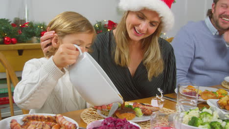 son pouring gravy onto his food as family eat christmas meal