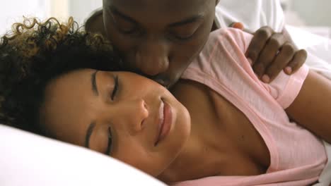 Young-couple-embracing-while-lying-on-bed