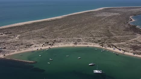 retiro aéreo de la bahía de agua de la isla desierta, agua de color esmeralda con pequeños barcos amarrados, algarve
