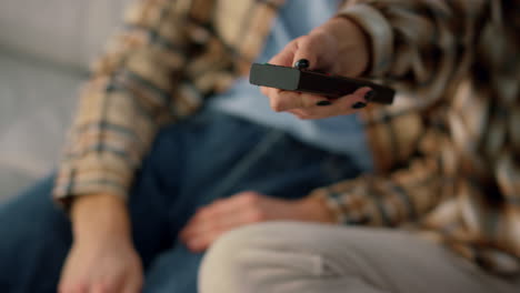 Husband-hand-holding-tv-remote-closeup.-Unknown-wife-taking-controller-pointing.