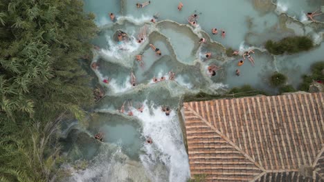 people bathing in natural waterfalls and hot springs of saturnia