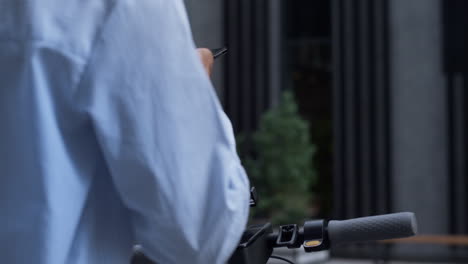 closeup woman hands rent electric scooter putting smartphone on handlebar.