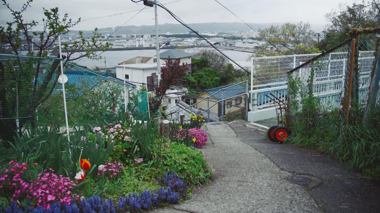 Coastal town of Saikazaki with colorful flowers on a path leading to a harbor