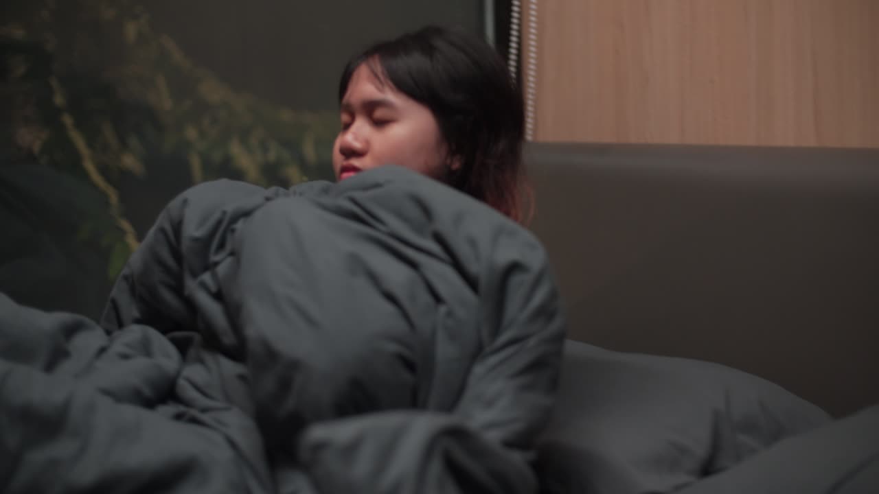 Sleeping Indonesian girl wrapped in blanket inside a cabin, peaceful mood