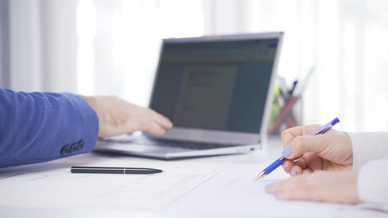 사무실 직원들의 가까운 손. 남자는 노트북을 사용하고, 여자는 프로젝트에서 그림을 그립니다.