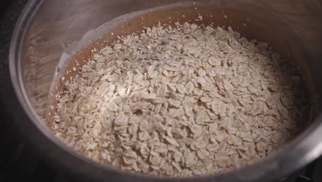 pouring oats into metal bowl with chocolate batter, baking a delicious chocolate oat cake - steady shot