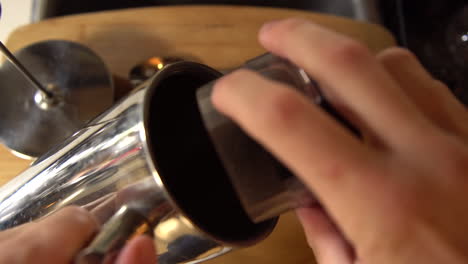 Top-down-shot-of-a-man-pouring-coffee-grounds-into-a-french-press