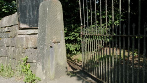 Cemetery-gates-in-high-summer,-gravestones,-trees-and-stonewalls-in-Yorkshire,-UK