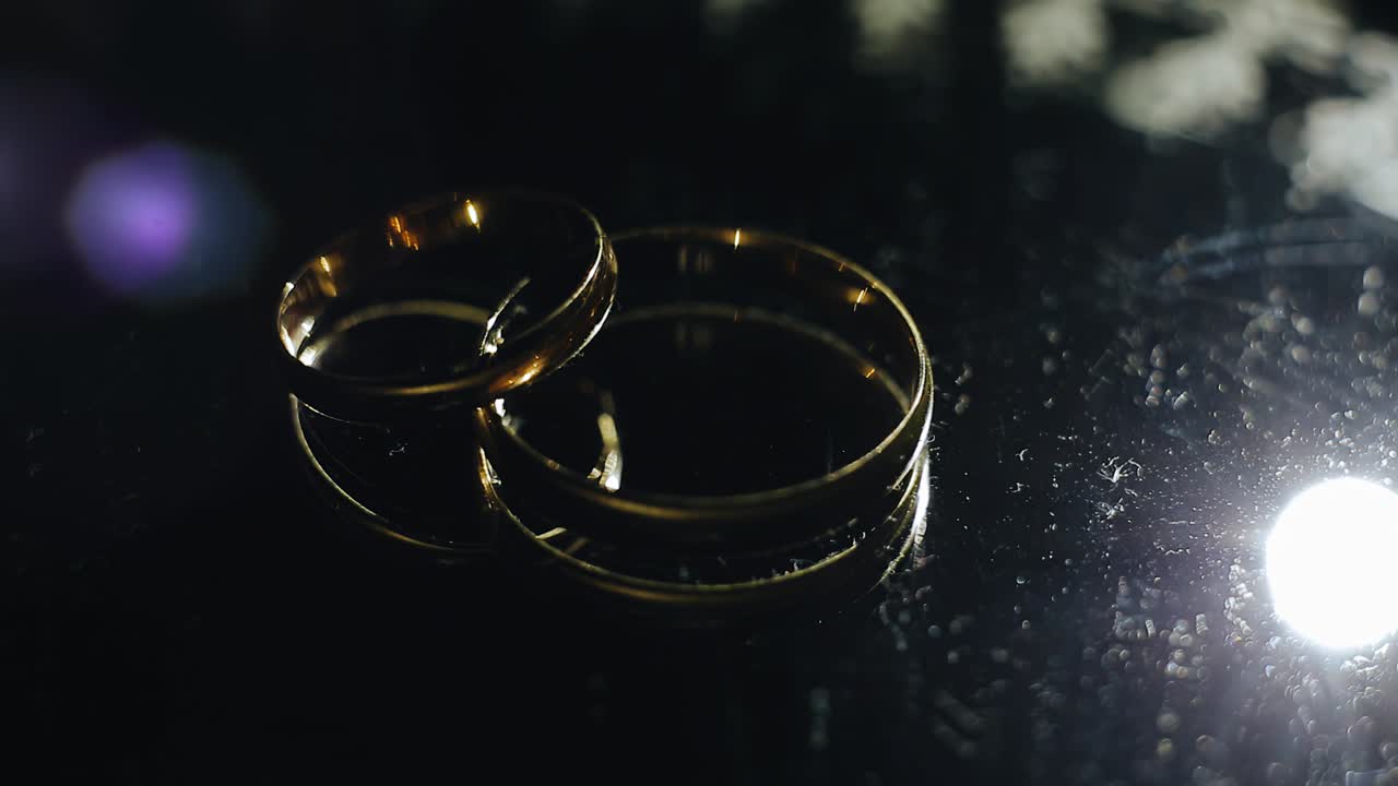 두 개의 아름다운 황금 결혼 반지에 역동적인 빛이 떨어집니다. 휴일 물건의 클로즈업