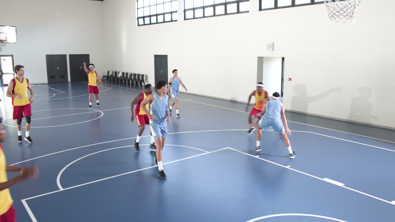 Basketball players in action on indoor court, competing with intensity and focus