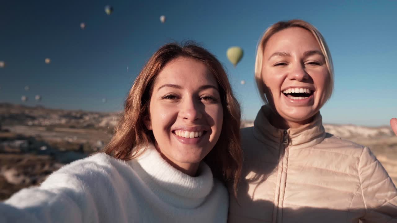Duas Mulheres Felizes Tirando Selfie com Balões de Ar Quente no Céu