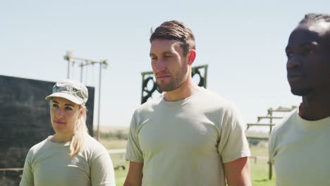 tres soldados diversos de pie escuchando instrucciones en el curso de obstáculos del ejército en el sol