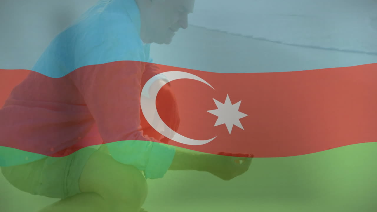 Agachado en la playa, persona sosteniendo un objeto pequeño con animación de la bandera de Azerbaiyán
