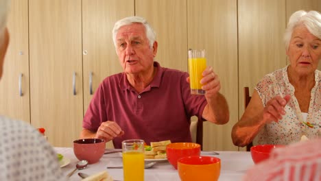 Älterer-Mann-Röstet-Sein-Glas,-Während-Er-Mit-Freunden-Isst