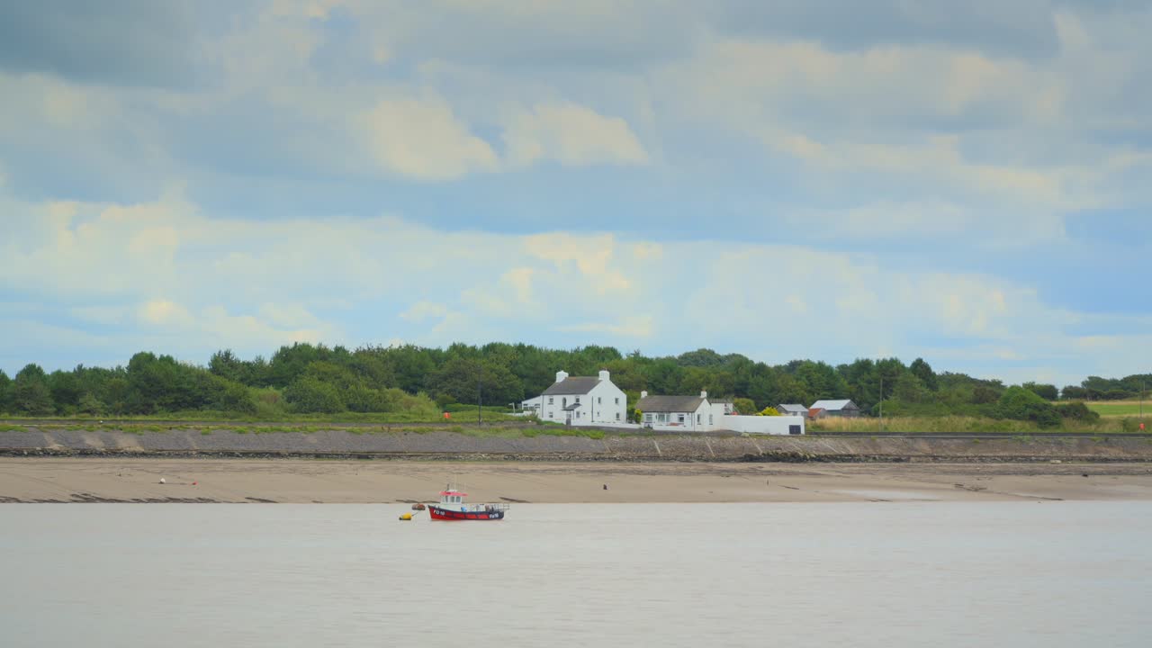 повышающийся прилив с небольшой лодкой и белым домом с гоночными облаками и бассейнами света на линии деревьев