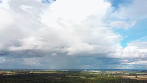 El-Arco-Iris-Sobre-El-Campo-De-Cultivo-Con-Trigo-Floreciente,-Durante-La-Primavera,-Vista-Aérea-Bajo-Nubes-Pesadas-Antes-De-La-Tormenta-1