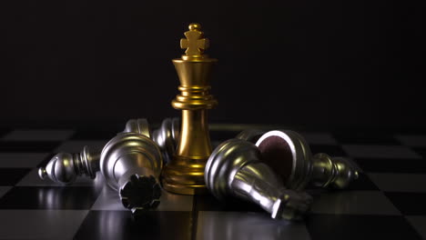 Cinematic-shot-of-king-chess-pieces-on-a-chess-board,-yellow-figure-is-standing-straight-and-other-white-figures-are-lying-on-side