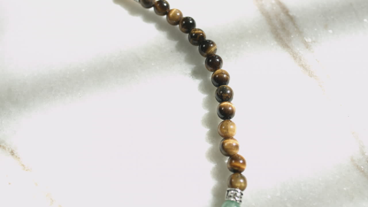 Slider shot of tiger eye beads placed on a white marble slab 4K UHD