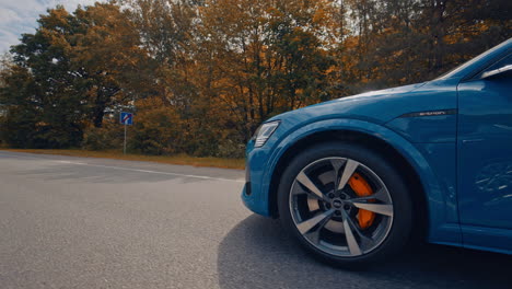 luxury car moving on a highway. beautiful blue electric audi car driving on a road on autumn trees background.