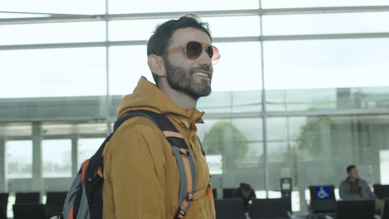 A handsome and young traveler smiles at the departure gate inside the airport building