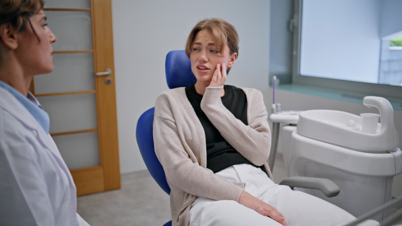 Patient complaining dental pain in stomatology clinic closeup. Woman dentist