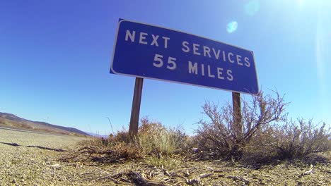 a sign on a lonely desert road warns that the next services are 55 miles away