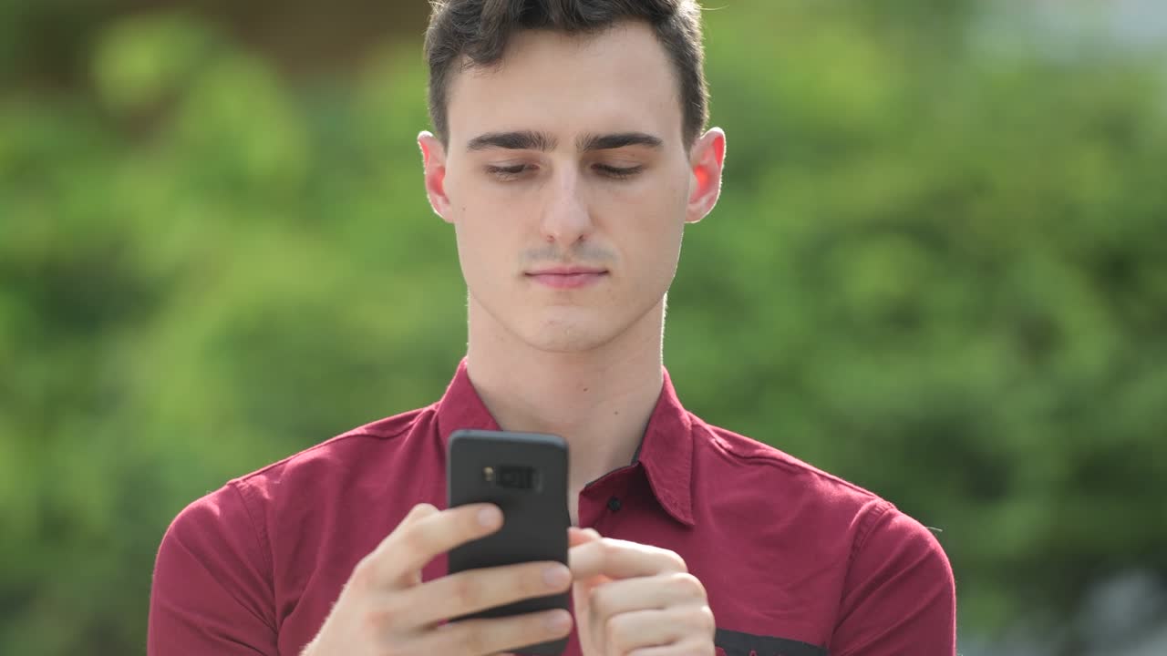 젊은 잘생긴 사업가가가 거리에서 드폰을 사용하고 있습니다.