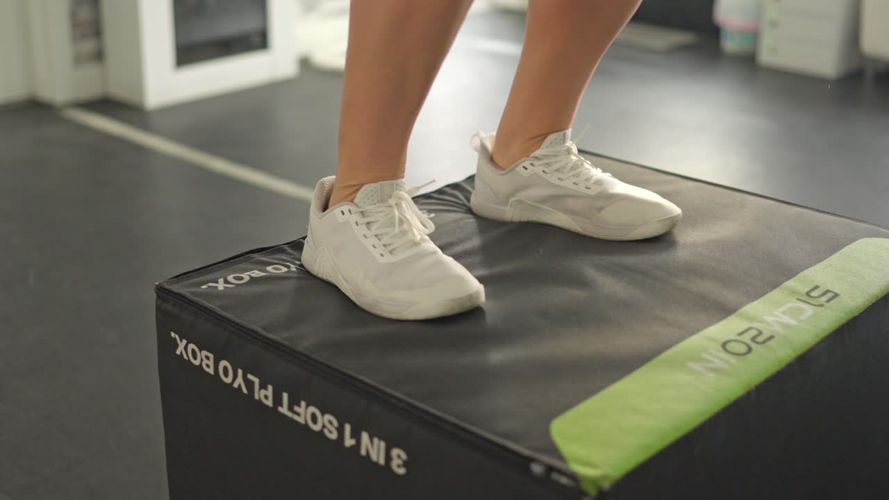 Persona che esegue box jump su una plyometric box in palestra
