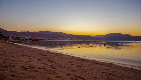 Zeitraffer-Eines-Wunderschönen-Sonnenaufgangs-über-Den-Bergen,-Während-Touristen-Einen-Strandspaziergang-Genießen