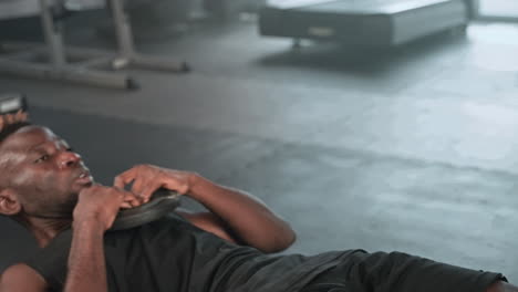 man doing weighted sit-ups in gym
