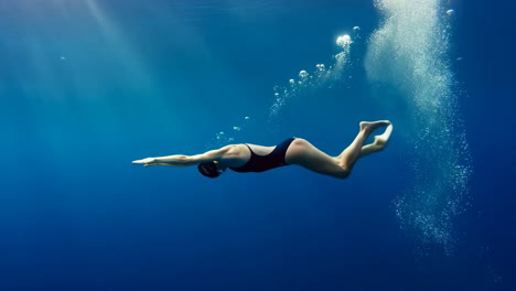 underwater swimmer diving in blue water