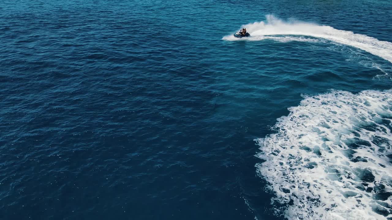 dos personas están montando motos de agua, jet ski, haciendo círculos y movimientos giratorios en la superficie del agua, atractiva vista aérea, capturada cerca de la costa de ibiza, españa