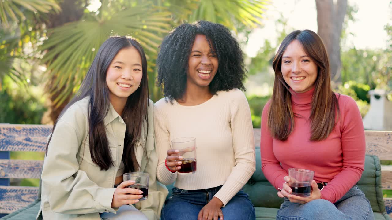 Multiethnic friends smiling at camera while drinking in the garden