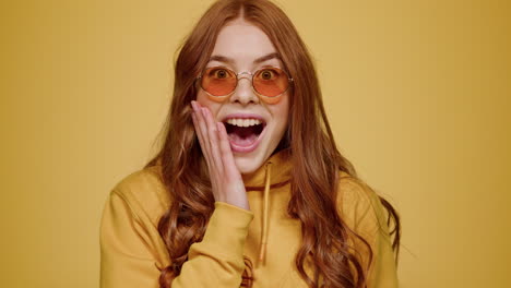 euphoric girl making hand gesture on orange background. woman acting indoors