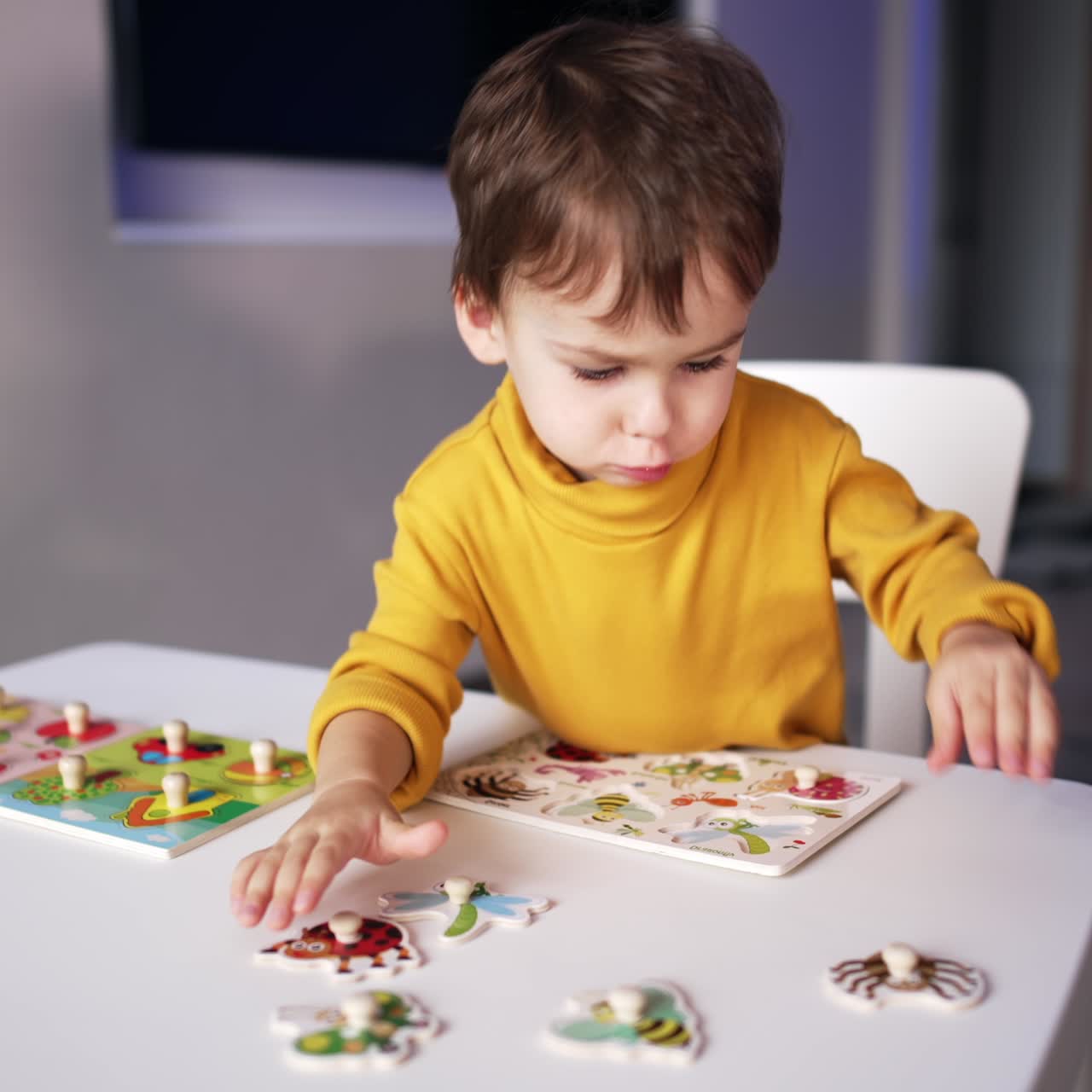 Bel bambino caucasico che gioca con i puzzle alla scrivania. Il simpatico bambino impara gli insetti attraverso il gioco.