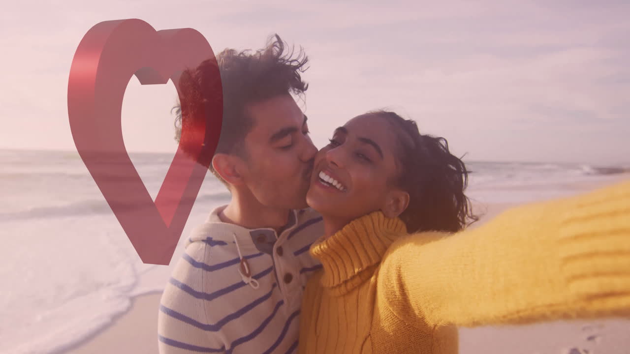 Taking selfie on beach, couple with heart animation overlay in background
