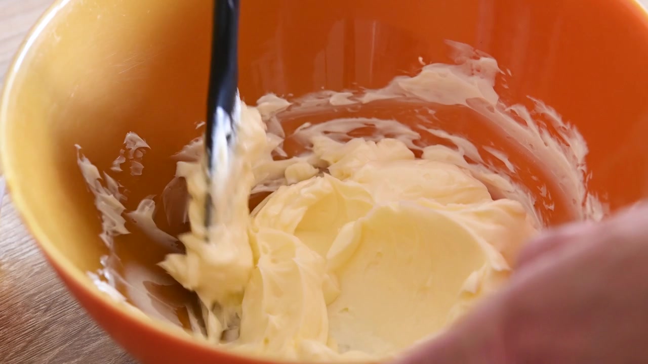 Person Mixing Softened Butter in an Orange Bowl