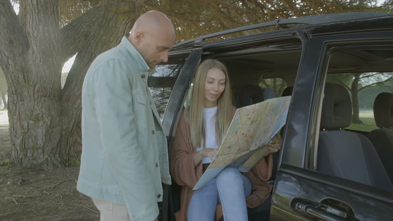 pareja feliz discutiendo el mapa en el coche