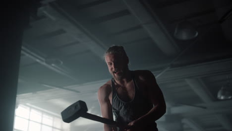 man using hammer for strength exercise. fitness guy hitting rubber tire