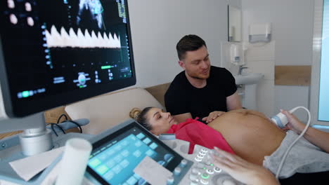 female obstetrician checks the pregnant woman on ultrasonic equipment. future parents look attentively on the monitor.