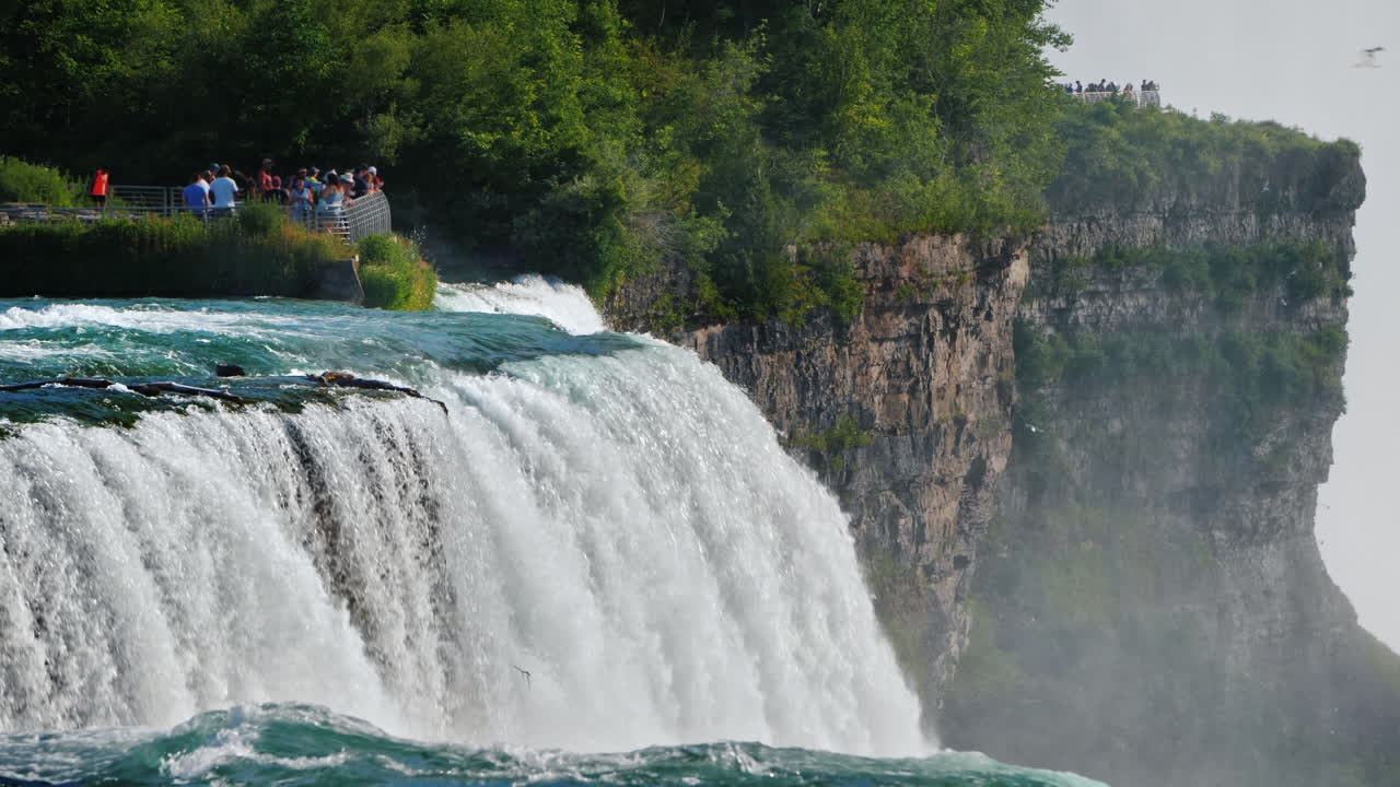엄청나게 아름다운 나이아가라는 관광객들이 걷는 전망대를 배경으로 폭포를 이룹니다.