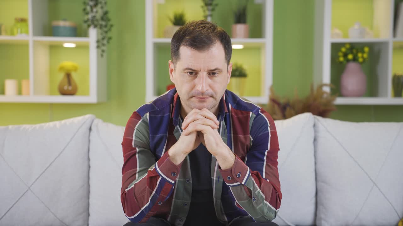 Uomo seduto in casa è nervoso, preoccupato e infelice