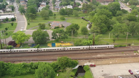 an aerial shot of a train leaving the station on a cloudy day in the evening