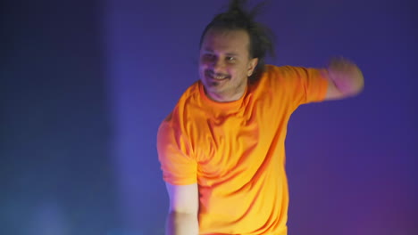 active jumping man looking at the camera. crazy man dancing in the neon light of the ridiculous dance. funny man on a colored blue background.