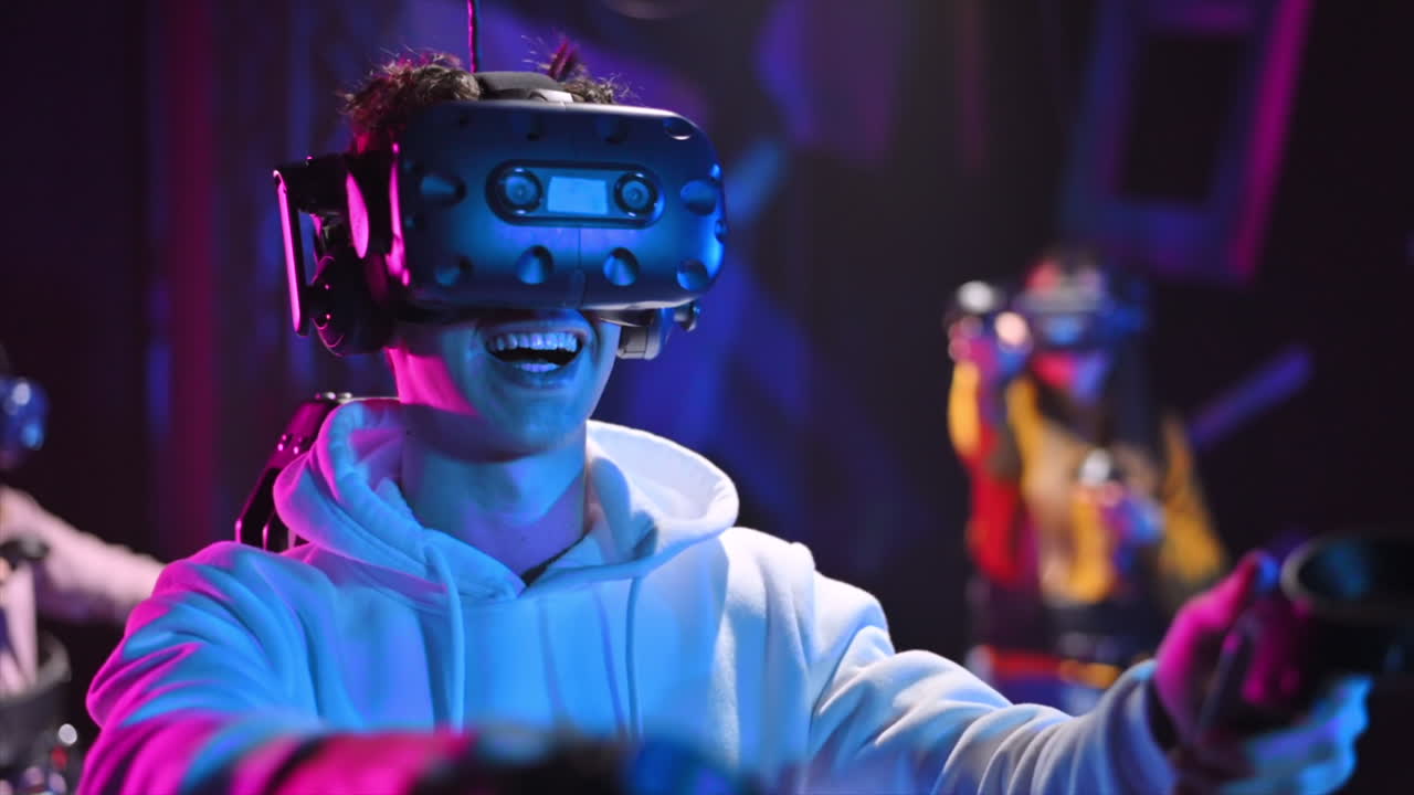 A joyful, shocked boy is playing on VR treadmill with helmet, controllers and a backpack. Other people playing nearby. Slow motion