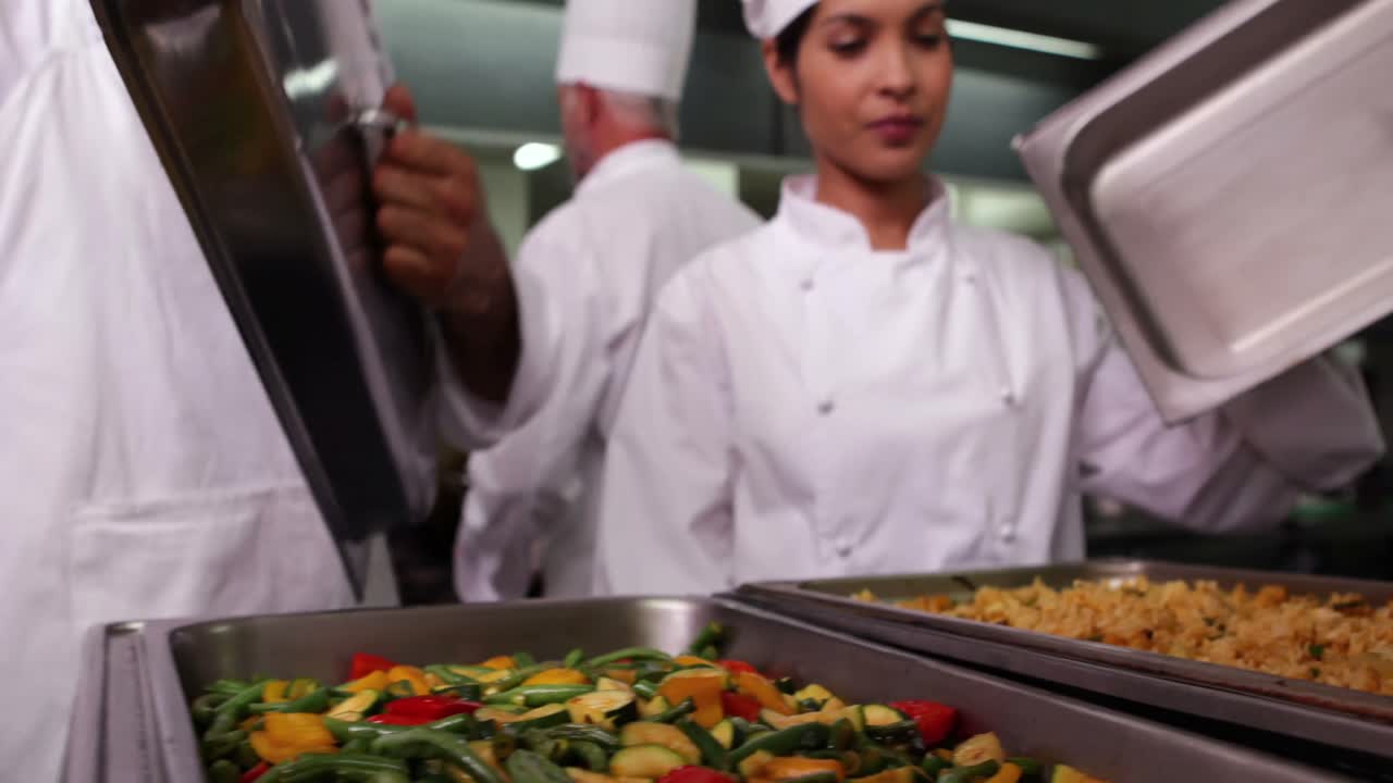 fila de chefs levantando la tapa de las bandejas de servicio