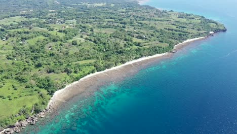 bird's eye view of green island surrounded by calm blue sea during summer in philippines