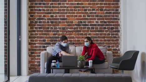 man and woman wearing face masks working together in office