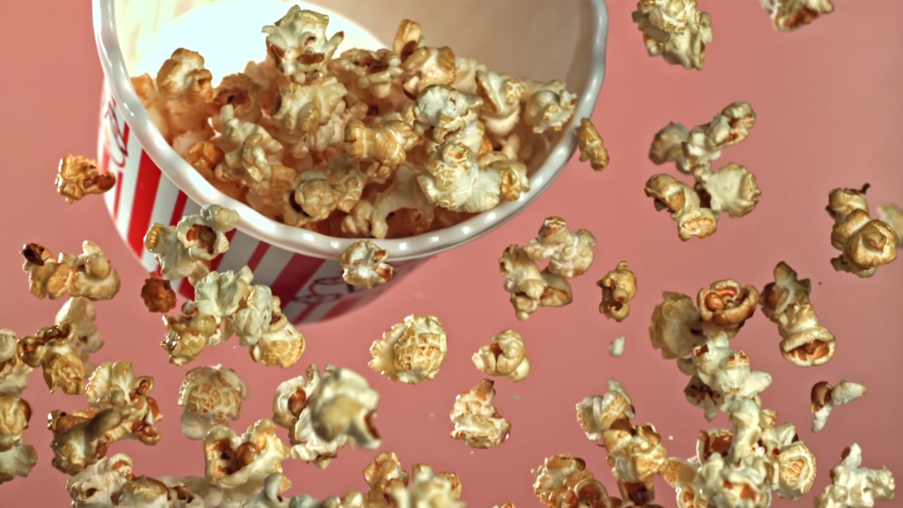 Palomitas de maíz con caramelo cayendo a cámara lenta de un cubo de palomitas